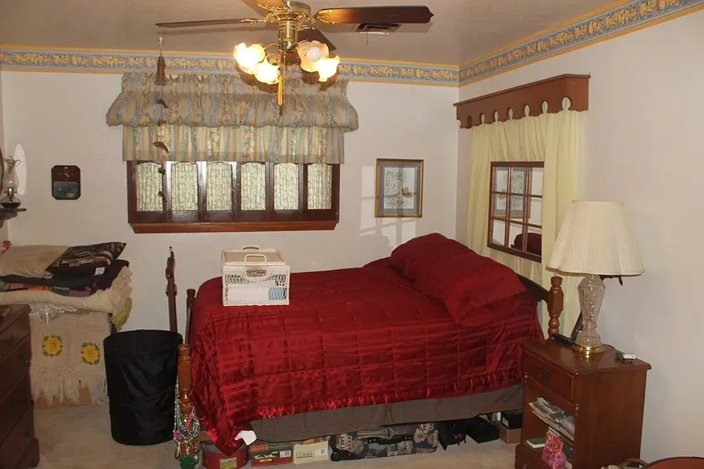 Bedroom before the remodel, with older carpet and furnishings