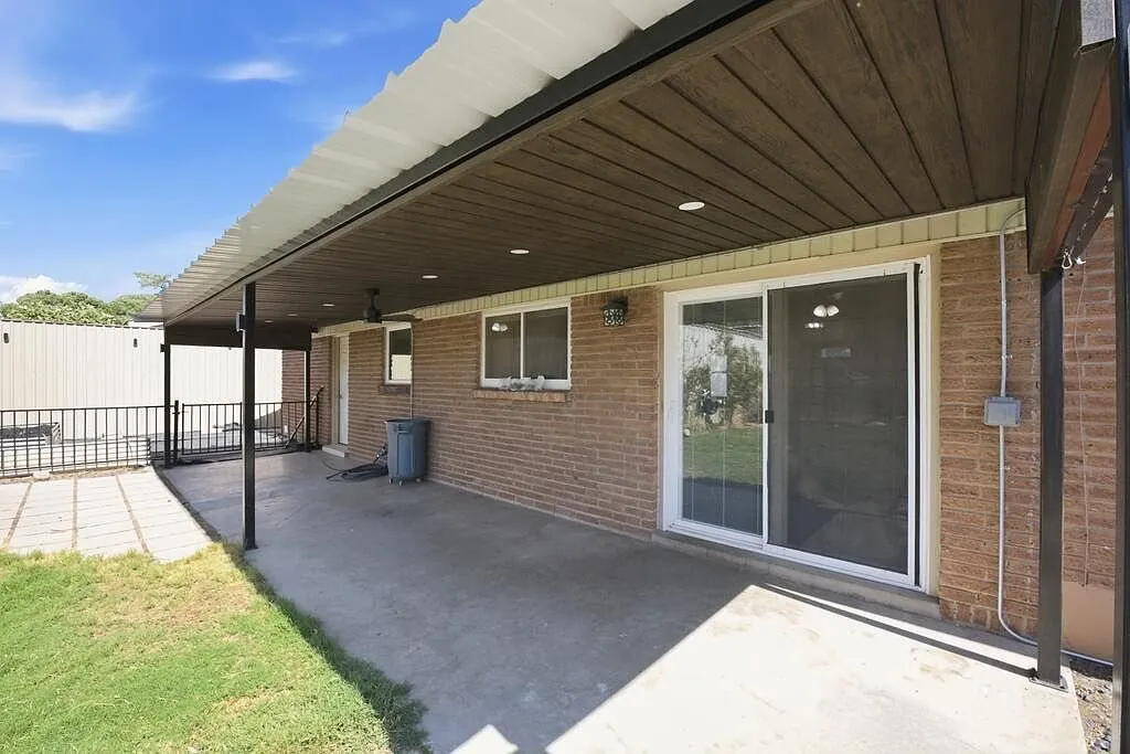 Covered back patio with a wood ceiling along a brick home