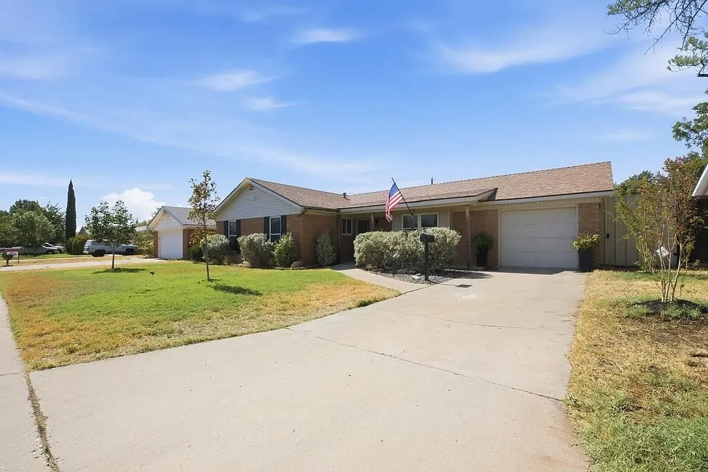 Front of the brick ranch home after the project, with landscaping and a clean driveway