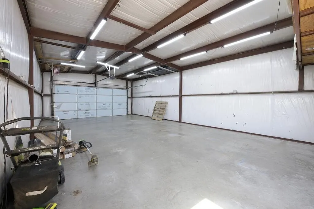 Interior of a steel shop with a roll-up door, LED lighting, and a slab floor
